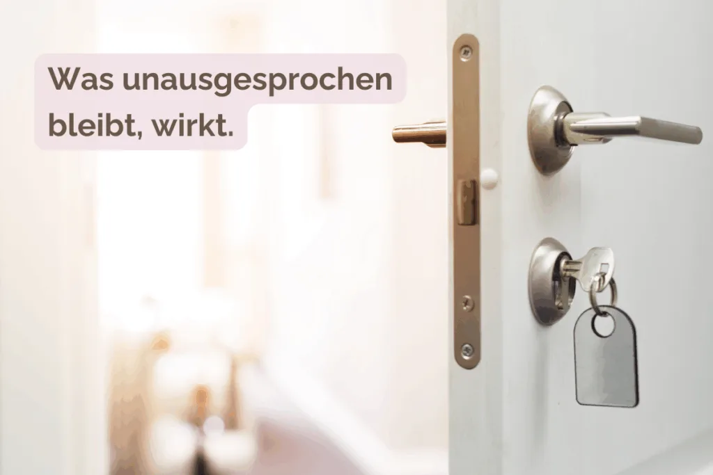 Eine geöffnete, weiße Zimmertür mit Schlüssel im Schloss ist zu sehen. Der Raum dahinter ist hell und unscharf. Das Bild wirkt offen und erzeugt durch das Unausgesprochene Spannung.